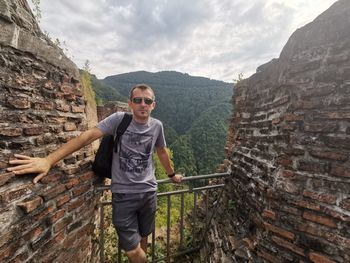 Full length portrait of young man standing against mountains