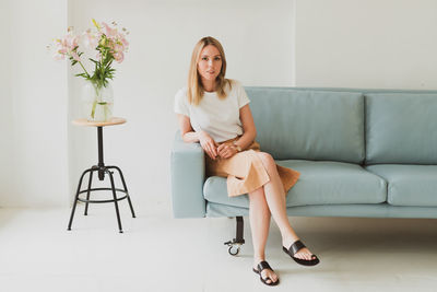 Portrait of young woman sitting on sofa at home