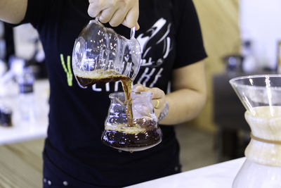 Midsection of man pouring wine in glass on table