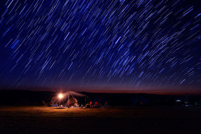 Scenic view of star trails over field at night