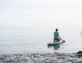 Rear view of man on sea shore against sky