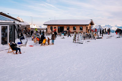 Panoramic view of people on snowcapped landscape against sky