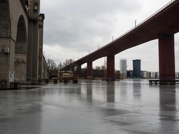 Bridge over river in city against sky