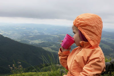 Rear view of woman standing against mountain