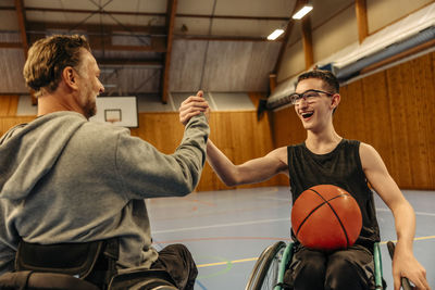 Cheerful male and female athletes with disabilities doing handshake while playing basketball at sports court