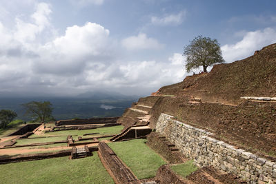 High angle view of old ruins against cloudy sky