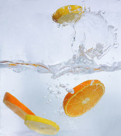 Close-up of orange slice in water against white background