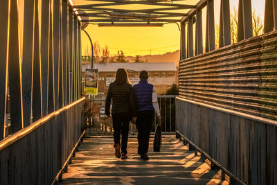 Rear view of people walking on walkway amidst buildings
