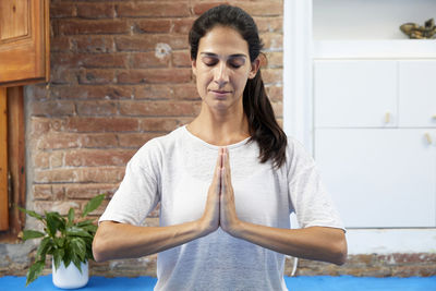 Portrait of young woman standing against wall