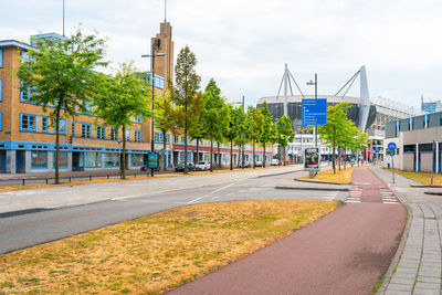 Road by buildings in city against sky