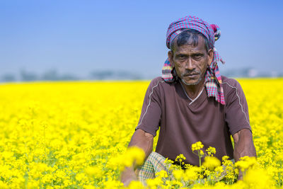Man standing by yellow flowers on field