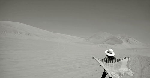 Monochrome image of a woman putting on her scarf at huacachina desert in ica region, peru