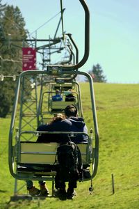 Rear view of people on chair lift against sky