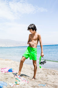 Boy standing on the beach with snorkel and mask