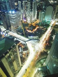 High angle view of illuminated street amidst buildings in city at night