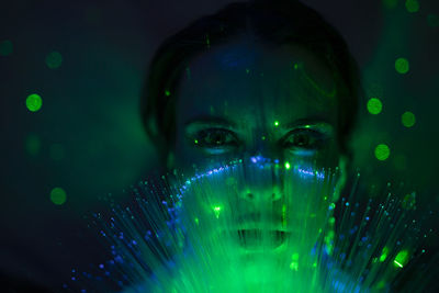 Close-up portrait of young woman against illuminated background