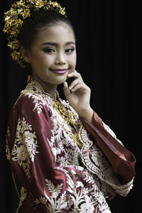 Portrait of smiling woman standing against black background