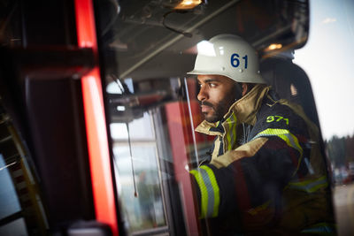 Confident firefighter looking away while sitting in fire engine