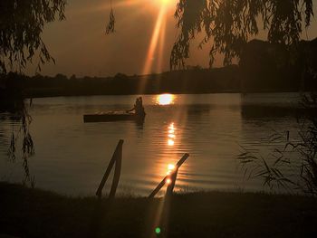 Silhouette trees by lake against sky during sunset