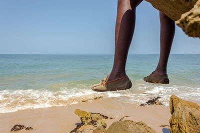 Low section of woman on beach against clear sky