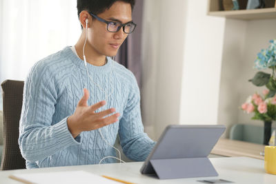 Midsection of man using mobile phone while sitting on table