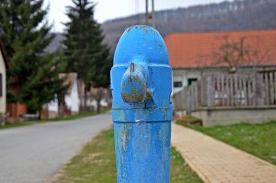 Close-up of blue water pump against houses