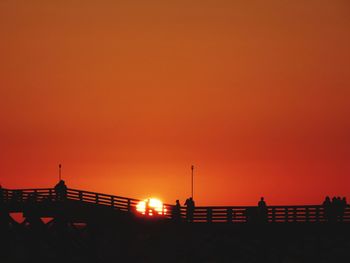 Silhouette bridge against orange sky