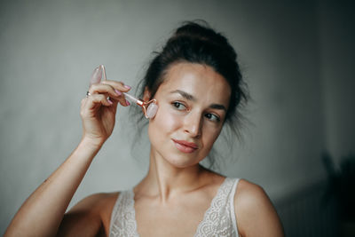 Brunette woman 30 years old doing face massage with a gouache scraper