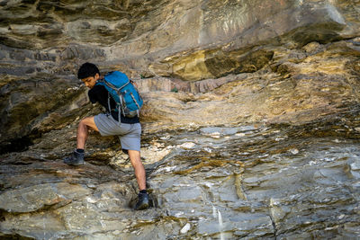 Young boy climbing the rocks wearing a backpack.