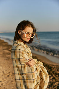 Young woman wearing sunglasses standing at beach