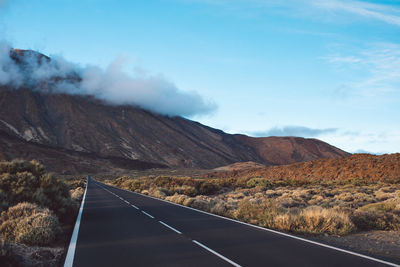 Road leading towards mountains against sky