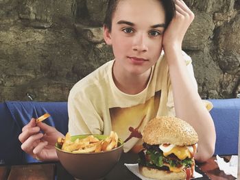 Boy eating french fries and burger at restaurant