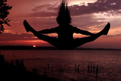 Silhouette person jumping against sky during sunset