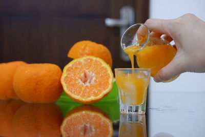Close-up of hand holding orange juice on table