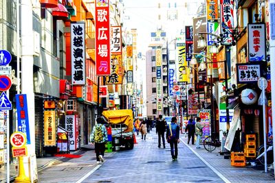 People walking on street amidst buildings in city