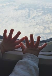 Close-up of cropped hand against sky