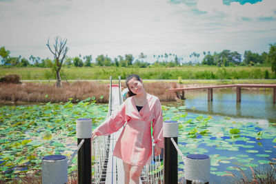 Portrait of woman standing by plants against sky