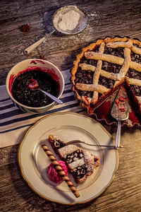 High angle view of cherry pie with ice cream and chocolate roll in plate