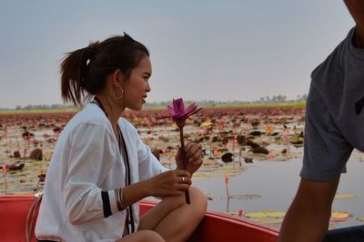 Side view of woman sitting on landscape against clear sky