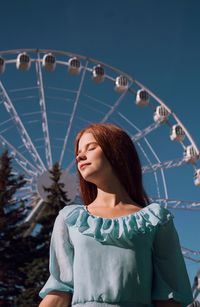 Young woman looking at carousel in amusement park
