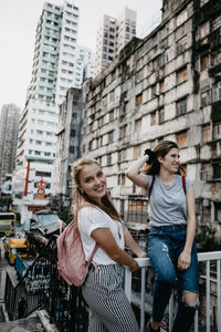 Smiling friends against buildings in city