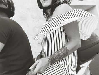 Midsection of man and woman sitting on motor scooter