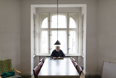 Senior man reading book at table at home