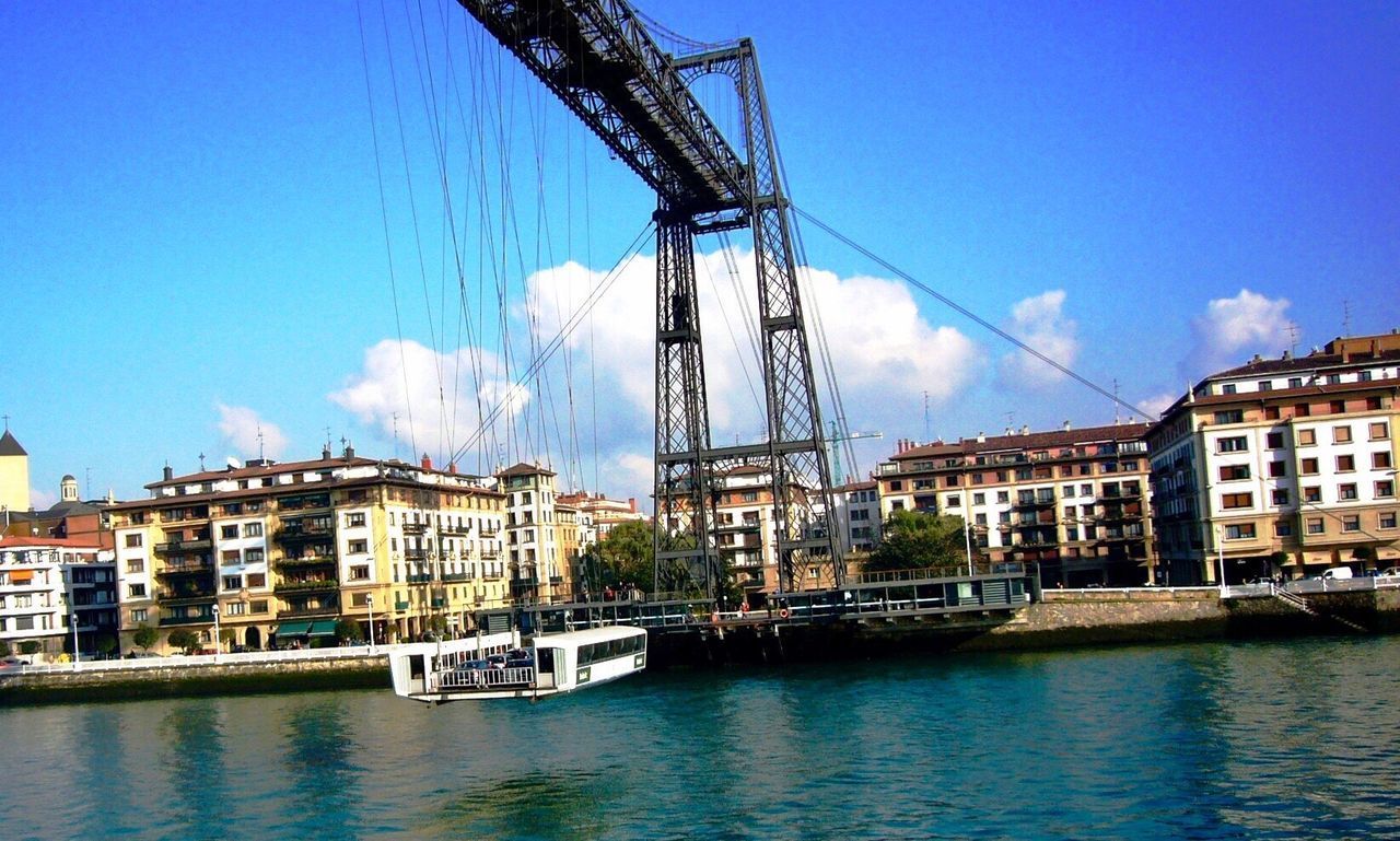 BOATS IN RIVER AGAINST CITYSCAPE