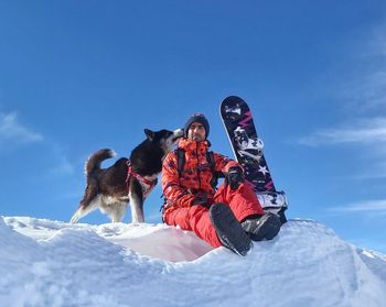 Low angle view of dog on snowcapped mountain against sky