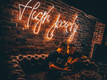 People sitting by illuminated light painting at night