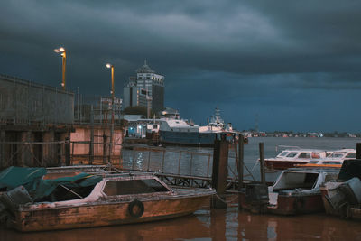 Boats moored at harbor against sky at dusk