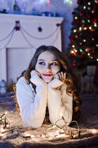 Smiling young woman lying on floor at home