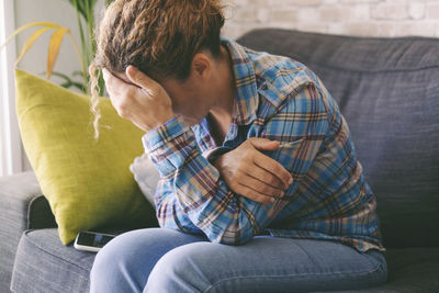 Young woman using phone while sitting on sofa at home