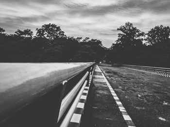 Empty road along trees and plants against sky